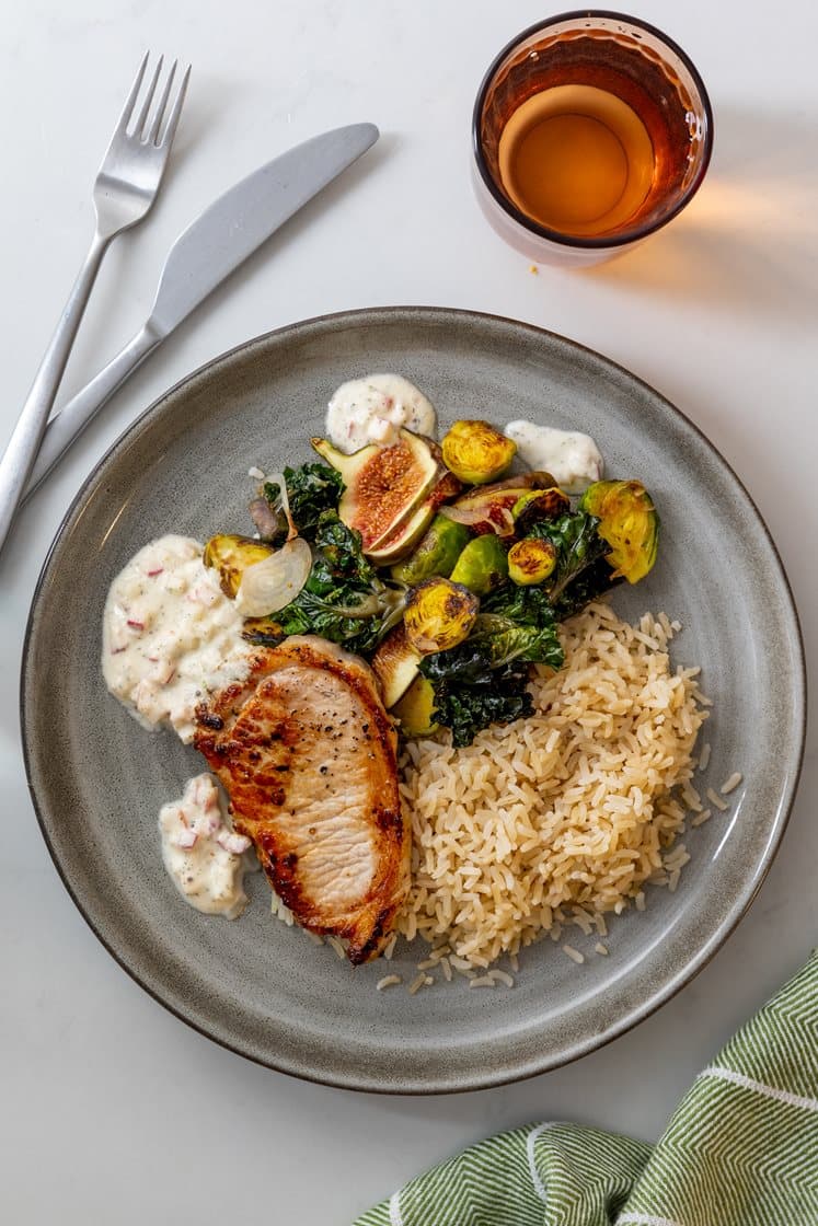 Mager svinekam servert med stekt rosett- og rosenkålsalat, fullkornsris og kremet epledressing