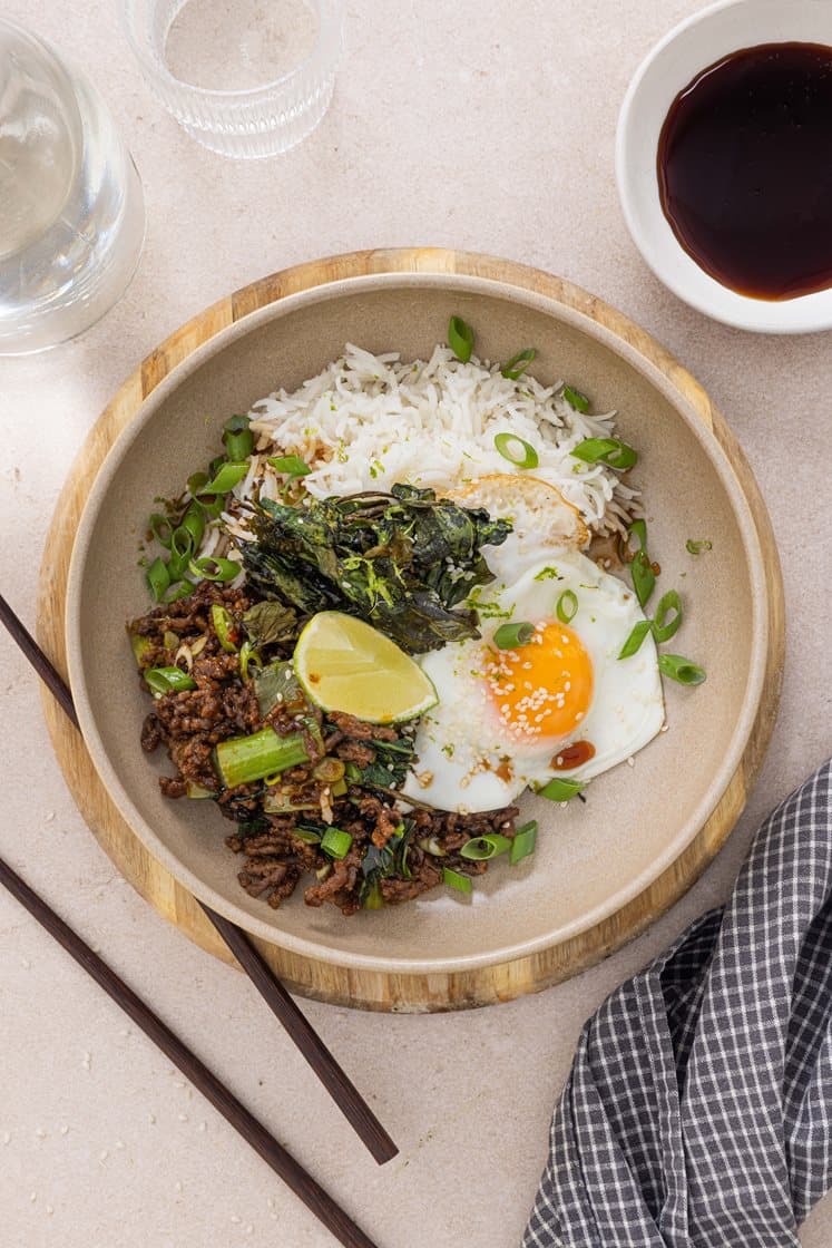 Bowl med hoisinstekt kjøttdeig, pak choy og spinatchips, servert med speilegg og vårløk