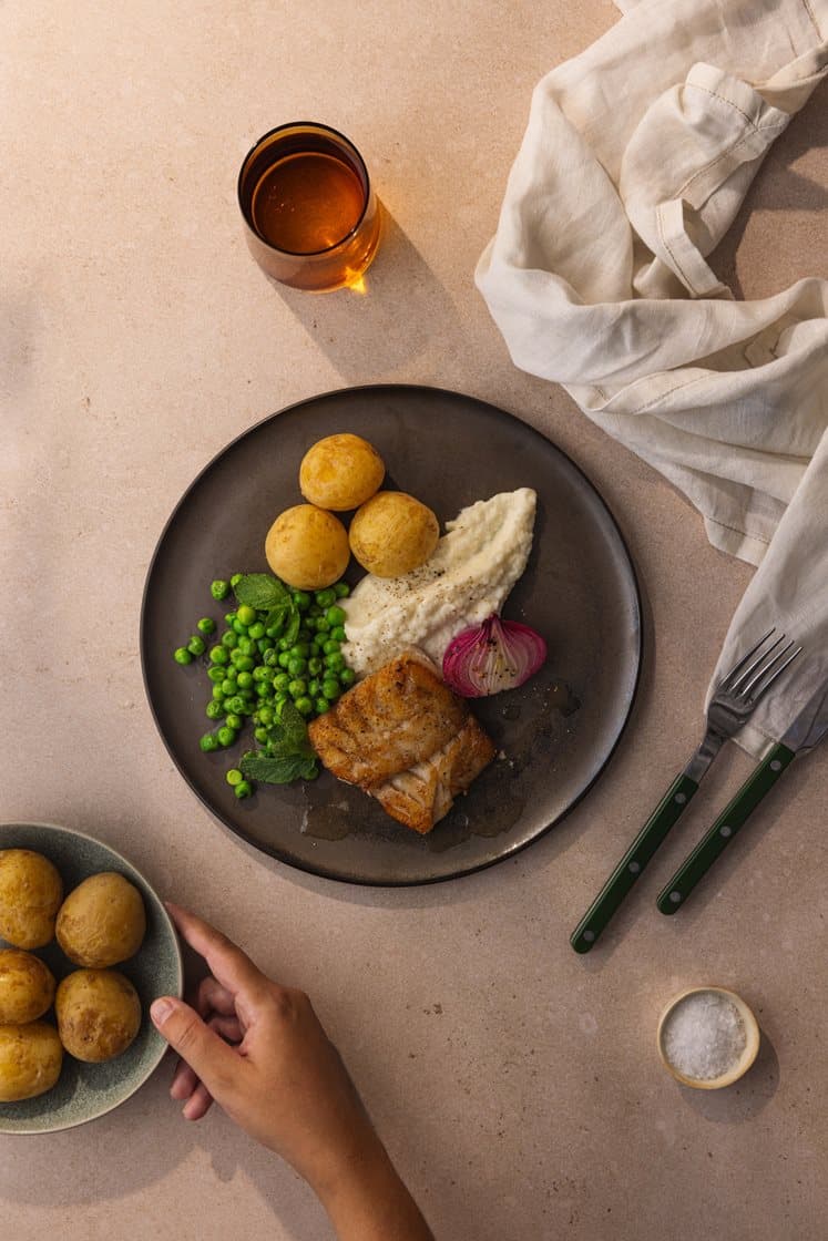 Torskefilet med mørbakt rødløk, sellerirotpuré, kokte poteter og mynteglaserte erter