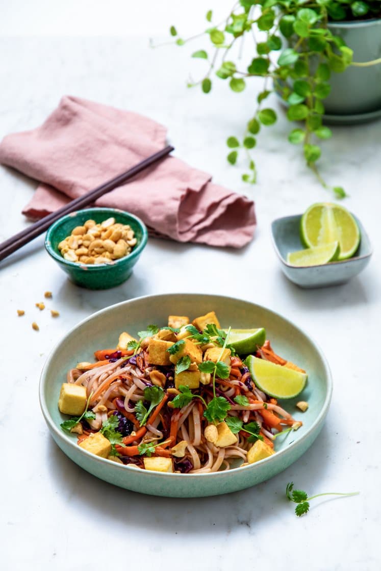 Pad thai med eggenudler, tofu og bønnespirer, toppet med peanøtter og frisk koriander