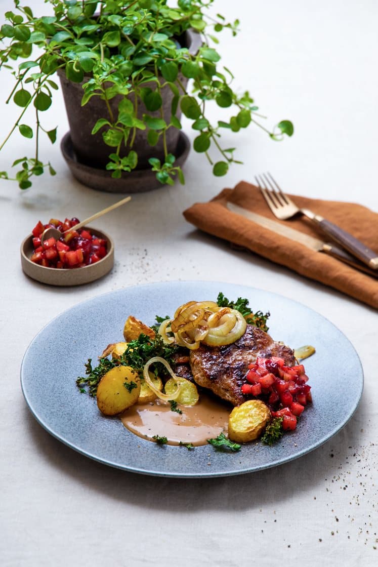 Saftige karbonader med stekt løk, tyttebærglasert eple, peppersaus og potetskiver med grønnkål