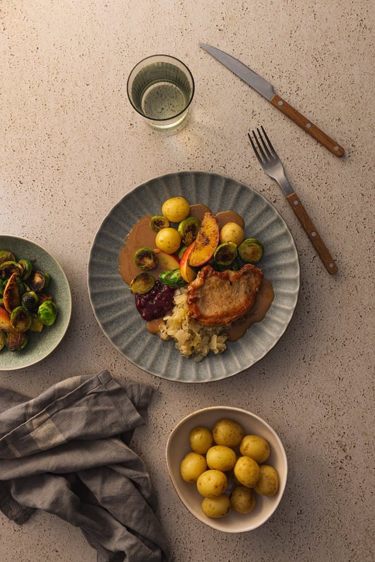 Svinekam med surkål, eple og rosenkål, servert med soppsaus og rørte tyttebær