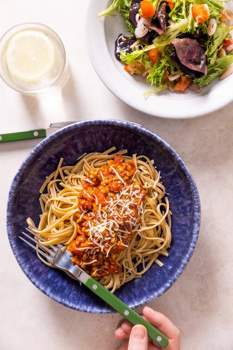 Rask linse-bolognese og pasta, servert med tomatsalat og revet Grande Premium
